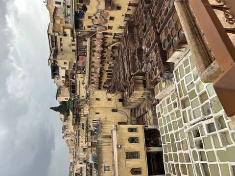 High viewpoint across the aged yellow walls and dye pits of Fes tannery under grey skies.