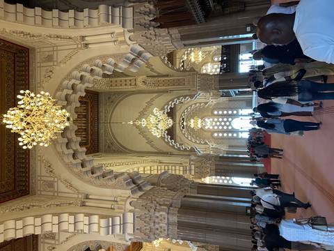 Visitors explore an ornate prayer hall with lavish chandeliers and scalloped arches inside the mosque.