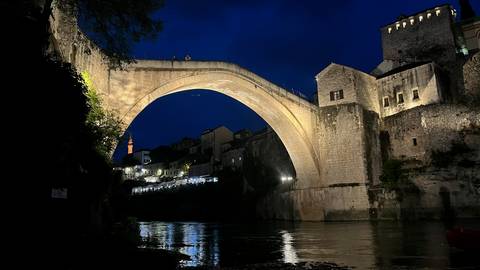 Stari Most bridge in Mostar beautifully lit at night spanning the Neretva River with reflections on the water.