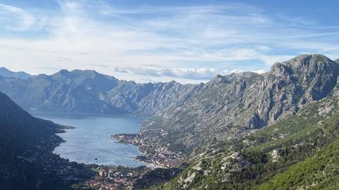 Panoramic view over the Bay of Kotor with dramatic limestone mountains and a coastal town far below.