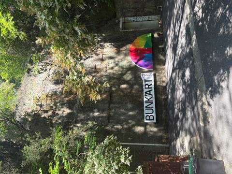 Concrete bunker entrance in a leafy setting with colourful BUNK'ART 1 logo banner.