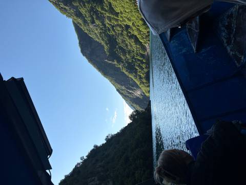 Boat gliding through the steep canyon walls of Lake Koman on a sunny morning.