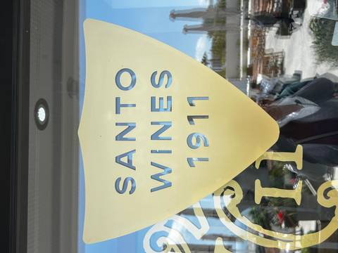Frosted glass door with large yellow shield logo reading 'Santo Wines 1911' reflecting outdoor terrace.
