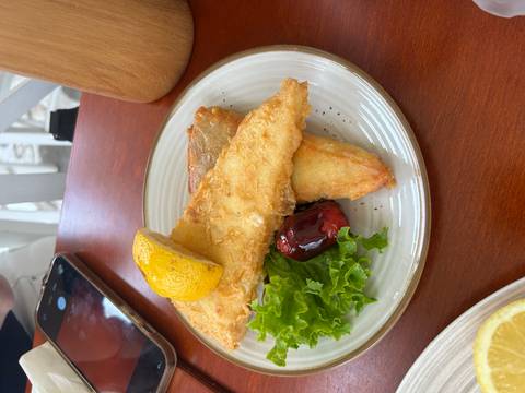 Plate of beer-battered fried fish with lettuce, roasted pepper and lemon wedge.