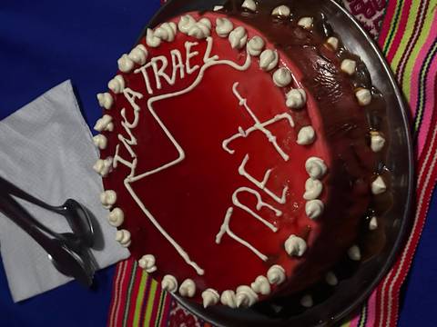 Bright red celebration cake decorated with white icing reading “Inca Trail Trex” and a mountain outline.