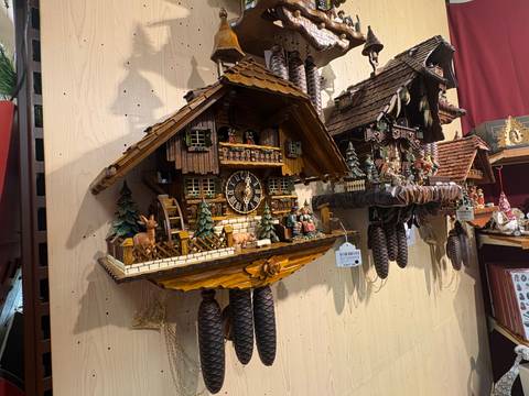Wooden cuckoo clocks and carved souvenirs hanging on a shop display.