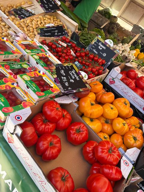 Close-up of vibrant red, orange and yellow tomatoes for sale at a French market.