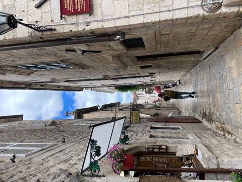 Back view of traveller walking down a quiet stone alley with hanging signs.