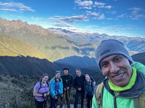 Smiling trekking group on the Inca Trail with dramatic Andean peaks behind.