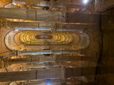 Golden arches and columns of the flooded Basilica Cistern reflected perfectly in still water.