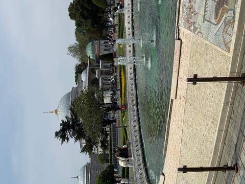 Low fountain pool and garden with domed Ottoman building in the background.