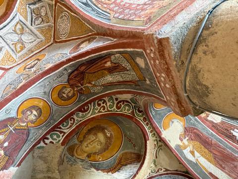 Frescoed ceiling of a cave church adorned with vivid Byzantine religious paintings.