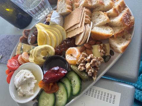 Close-up of a gourmet platter with cheeses, fruit, nuts, crackers and dips arranged on a ceramic plate.