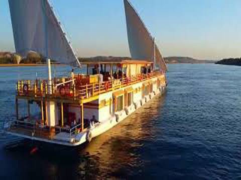 Passenger river vessel with large sails cruises along the Nile at sunset