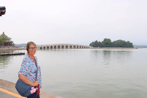Woman posing beside Kunming Lake with the 17-Arch Bridge of the Summer Palace in the distance