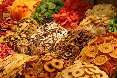 Colorful heap of assorted dried fruits and nuts displayed at a bustling market stall.