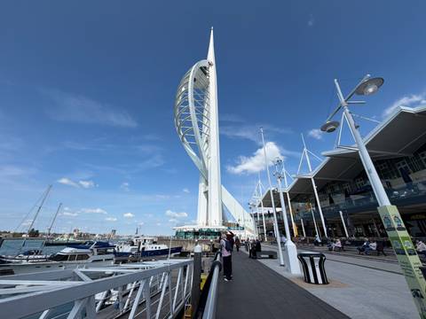 Ground view of Spinnaker Tower and marina promenade with visitors and moored yachts.