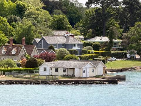 Charming waterfront cottages and manicured gardens along a wooded shoreline.