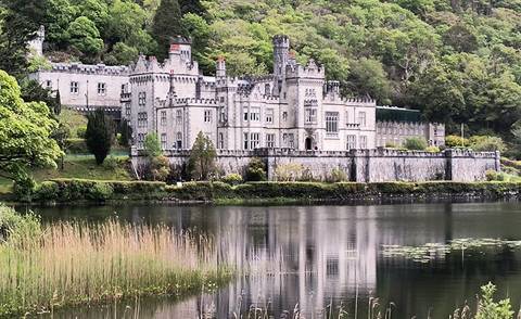 Kylemore Abbey reflected in still lake amid lush Connemara greenery.