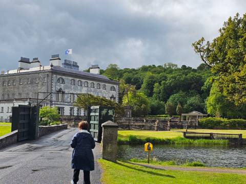 Visitor walking toward Westport House estate gardens and lake on overcast day.