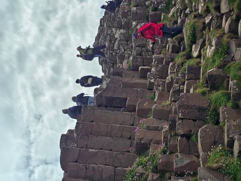 Visitors climbing the hexagonal basalt columns at Giant’s Causeway.