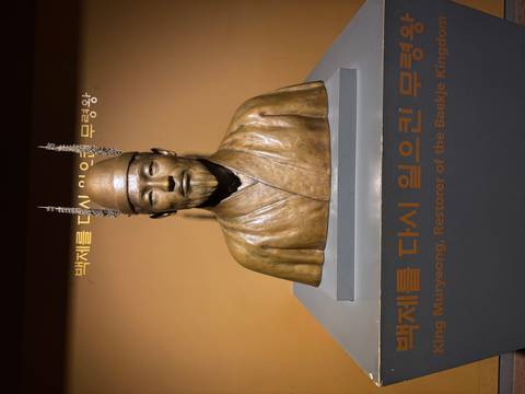 Bronze bust of King Muryeong displayed in a museum with Korean and English captions.