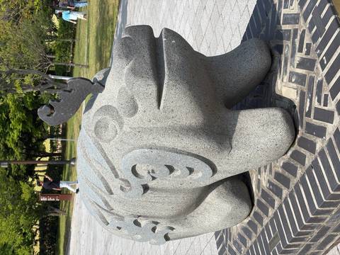 Close-up of a decorative stone animal statue in a park setting.