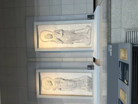 Stone relief panels depicting Buddhist figures displayed vertically in a museum gallery.