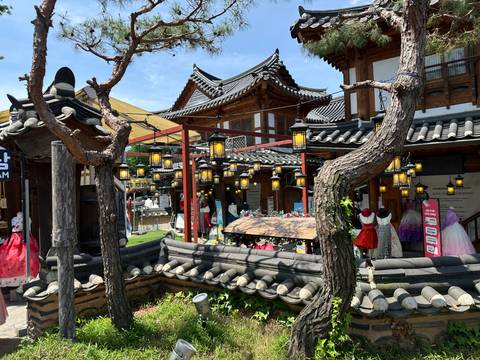 Traditional wooden hanok shops hanging paper lanterns and displaying colorful hanbok dresses.