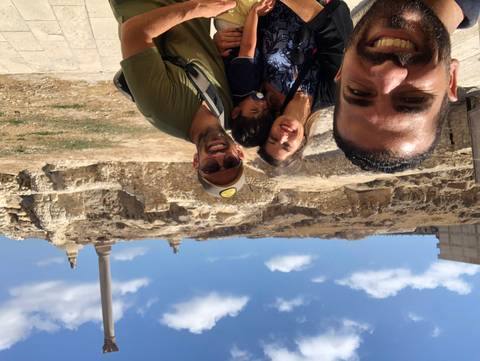 Family selfie with Pompey’s Pillar and blue sky in the background, child in front