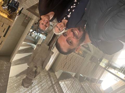 Three smiling travellers take a selfie with the Ramses II statue towering behind them inside the museum hall.