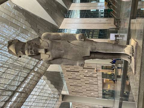 Full-length view of Ramses II statue bathed in skylight within the spacious atrium of the Grand Egyptian Museum.