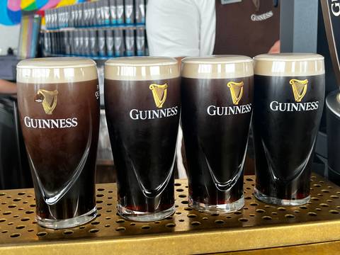 Four freshly poured pints of Guinness stout lined up on a bar drip tray
