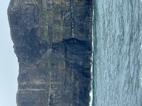 Sheer grey sea cliffs with rough Atlantic waves below on a cloudy day