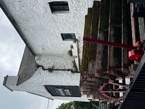 Old wooden water wheel against a white-washed stone distillery building