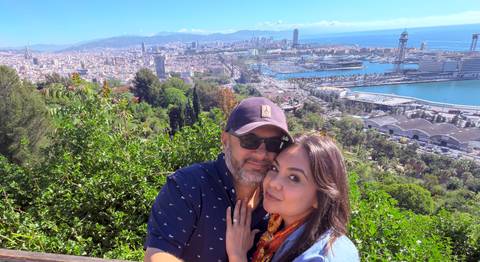 Couple posing with panoramic view of Barcelona harbor and skyline behind them