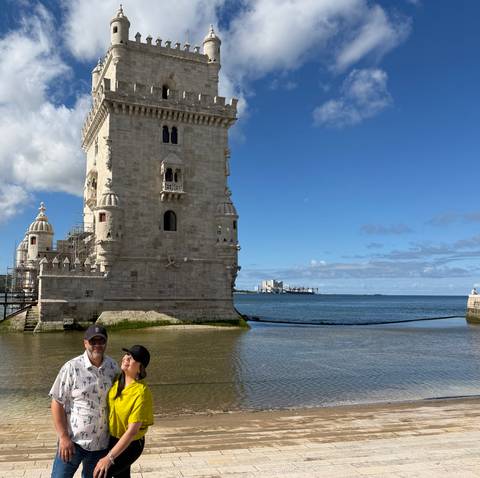 Couple standing in front of the historic Belem Tower beside the river