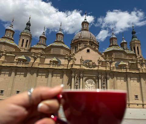 Blurred hand holding a coffee cup with ornate basilica domes in the background