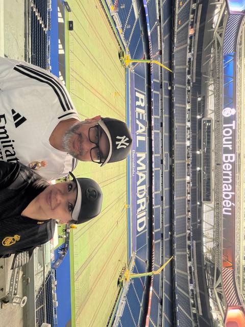 Selfie of a couple inside Santiago Bernabéu stadium with Real Madrid seats behind