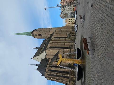 Gothic cathedral and modern fountain in spacious square on a clear day.