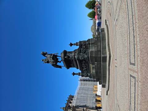 Equestrian monument standing alone in sunny plaza under cloudless blue sky.