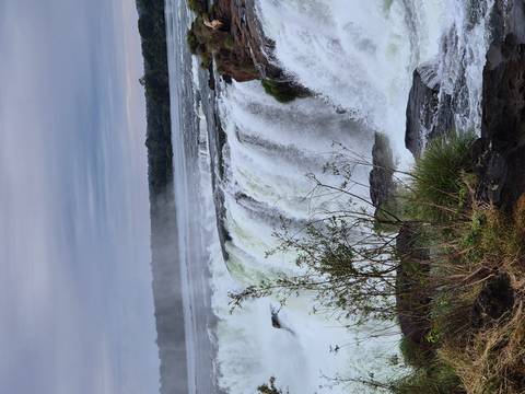 Powerful Iguazu Falls thundering over a rocky cliff with mist rising into the sky