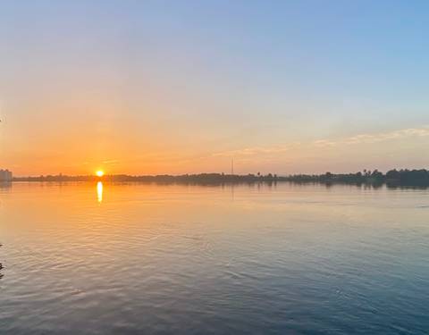 Soft sunrise over a wide calm river reflecting golden light on the water