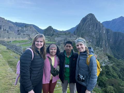 Group of hikers posing with Machu Picchu’s terraces and Huayna Picchu peak towering behind.