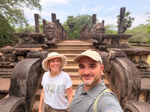 Couple selfie in front of ancient stone stairway flanked by guardian lion statues.