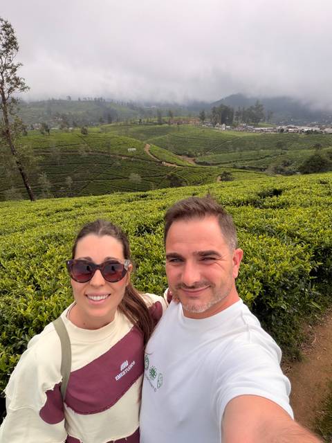 Selfie of couple amid rolling green tea plantations stretching over the hills.