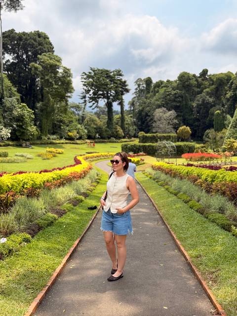 Woman enjoys colourful landscaped paths and flower beds in a lush botanical garden.