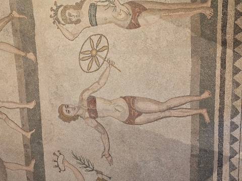 Ancient Roman mosaic depicting a young woman holding a disc, known from the Bikini Girls series.