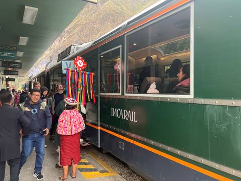 Busy platform scene as travelers board the green Inca Rail train decorated with colorful ribbons