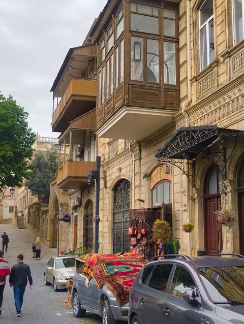 Charming narrow street with ornate wooden balconies, stone facades and decorative wrought-iron awnings in an old town.